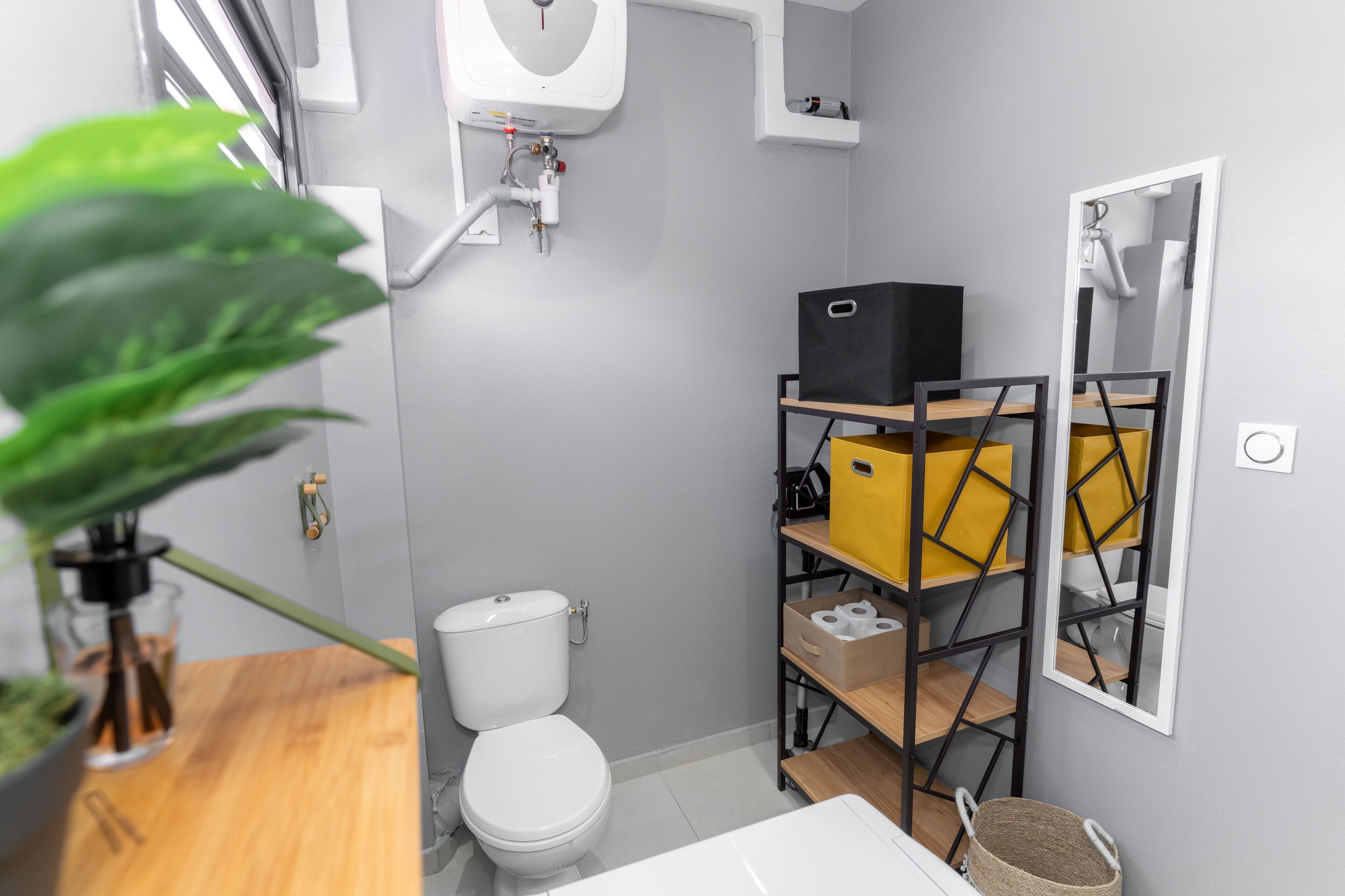 Een moderne badkamer met toilet, wastafel, spiegel en een plankje met toiletartikelen.