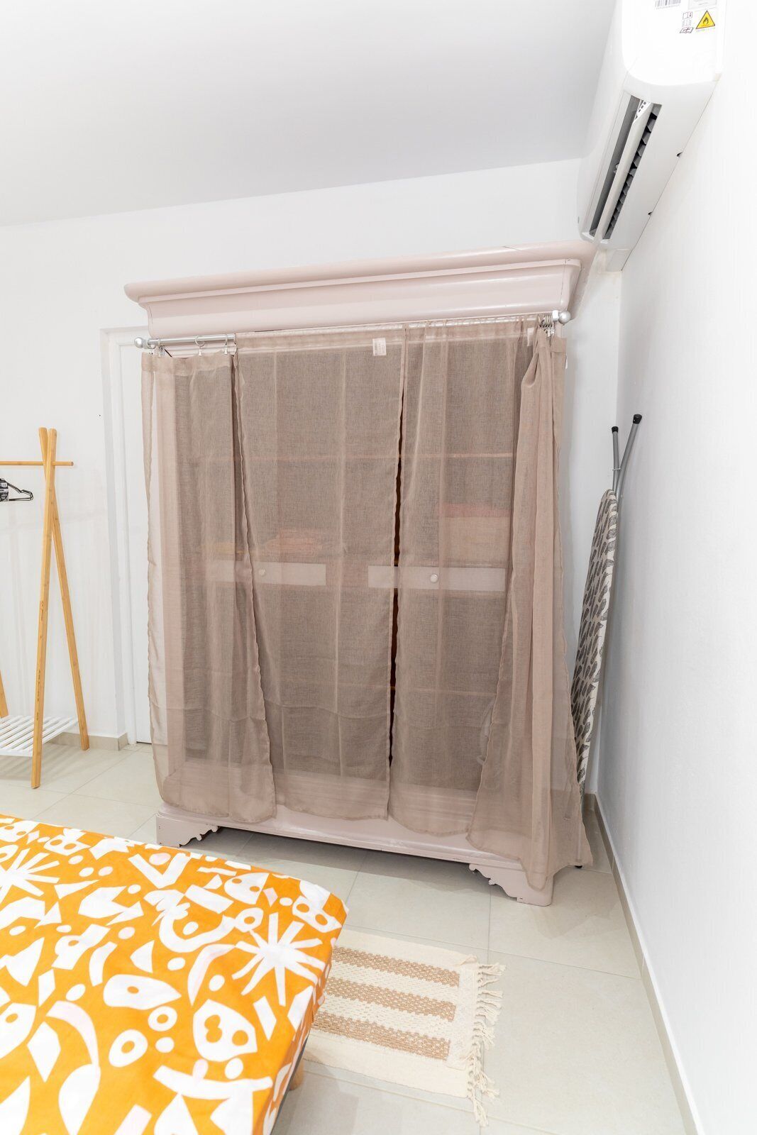 A bedroom with a bed, a wardrobe, a radiator, and a standing lamp.