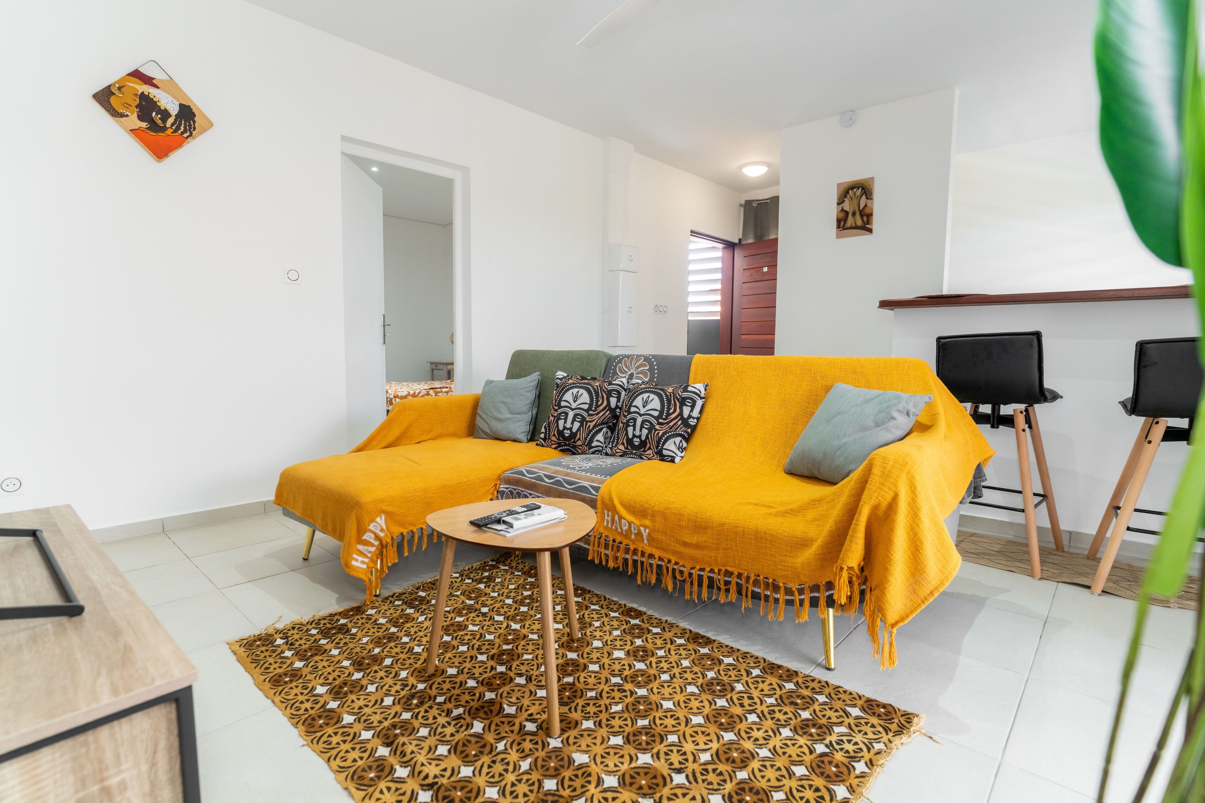A modern living room with a yellow sofa, a patterned rug, and a small wooden coffee table.