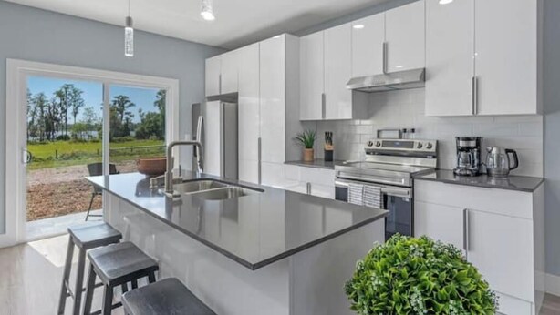 A modern kitchen with white cabinets, a central island, and a view of the outdoors.