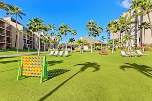 Un patio de hotel con palmeras, sillones de descanso y una zona de juegos para niños.