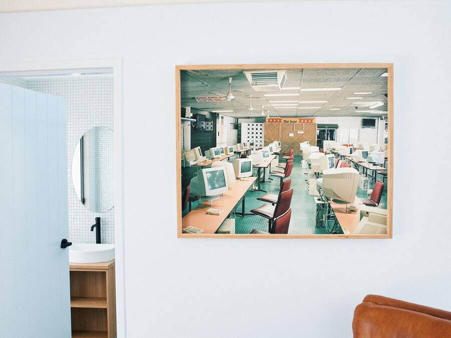 Una habitación con una butaca de cuero marrón, una puerta blanca y un cuadro con una imagen de un laboratorio de computación.