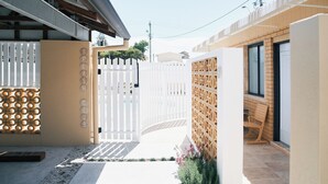 A gated entrance with a white picket fence, a wooden lattice wall, and a bench.