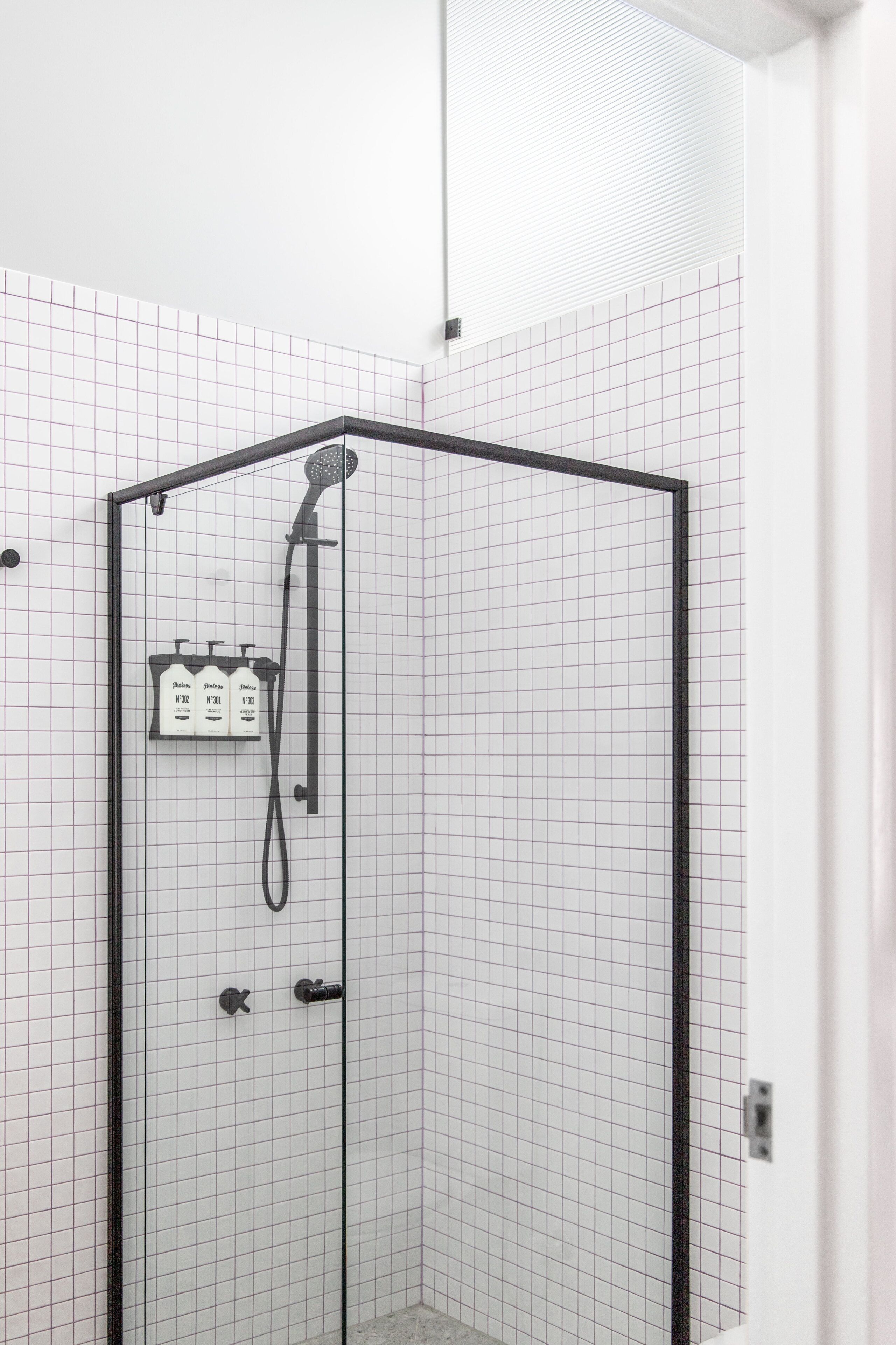 Une cabine de douche fermée par des parois en verre, dotée d’un pommeau de douche à main et d’un panneau de commande.