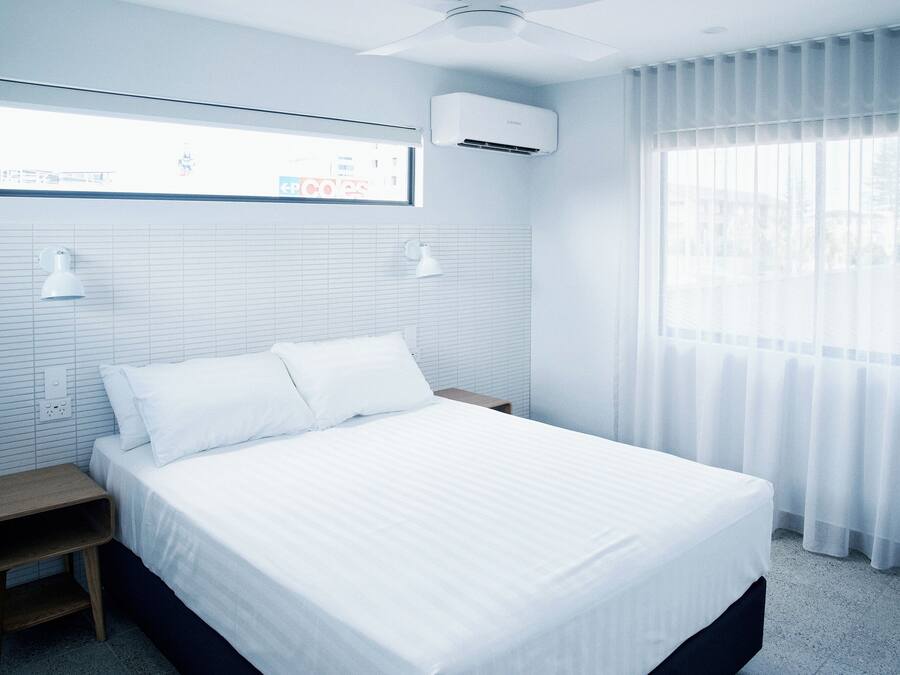 A bedroom with a bed, bedside tables, a ceiling fan, and a window with curtains.