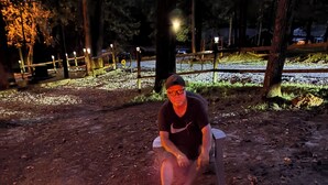 Une personne est assise près d’un foyer en pierre où brûle un feu.