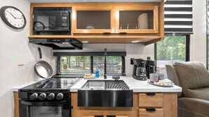 Une petite cuisine équipée d’un four à micro-ondes, d’une cuisinière, d’un évier et d’armoires en bois.