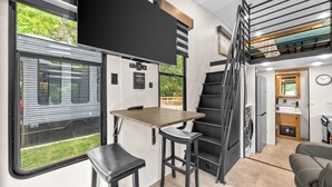 Un intérieur de camping-car compact comprenant une cuisine, un coin repas et un petit escalier.