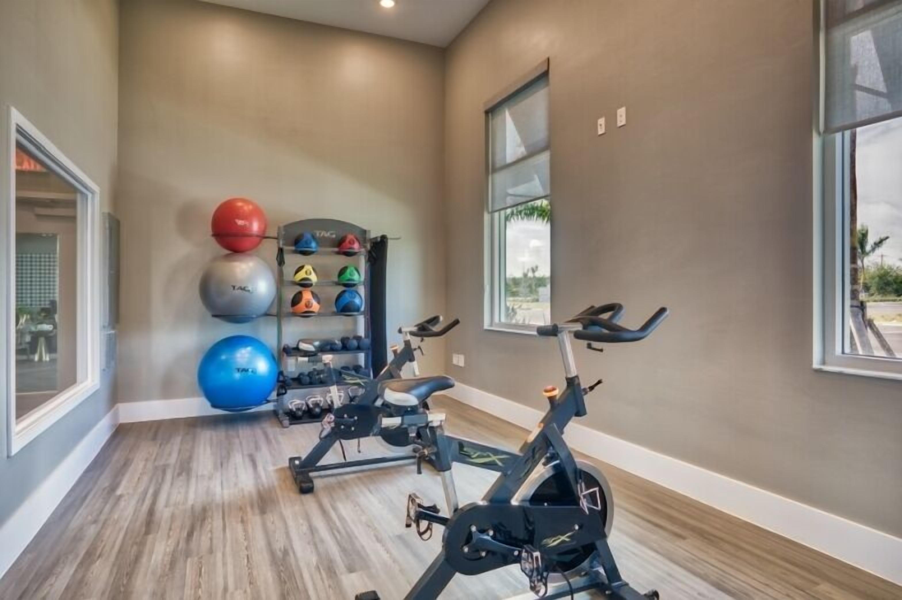 A gym with exercise bikes, a rack of helmets, and exercise balls.