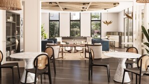 A spacious living area with a central coffee table, sofas, and two round tables with chairs.