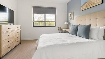 A bedroom with a bed, a dresser, a window, and a painting on the wall.