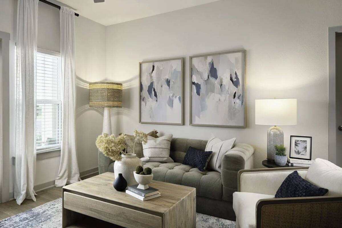 A living room with a sofa, a coffee table, and a lamp. There are two abstract paintings on the wall.