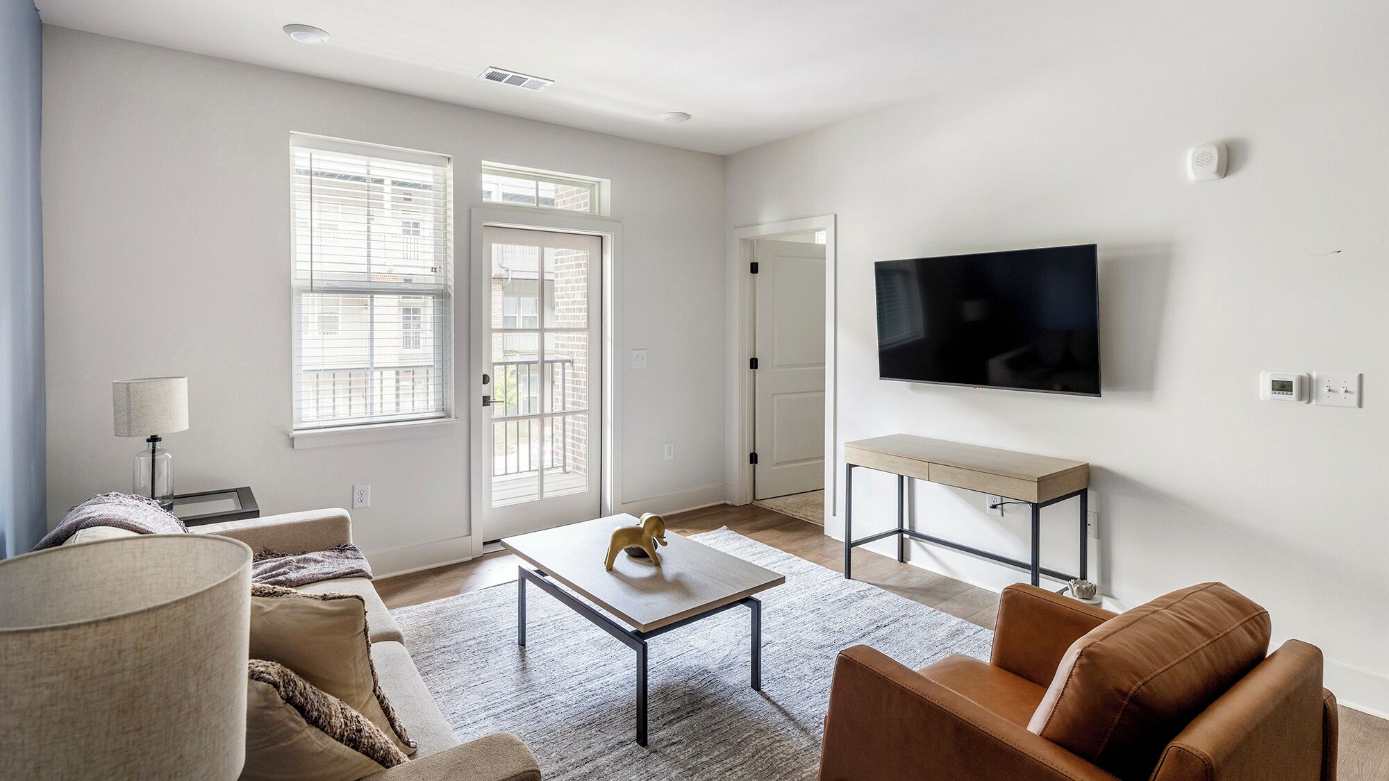 A modern living room with a flat-screen TV, a sofa, a coffee table, and a desk.