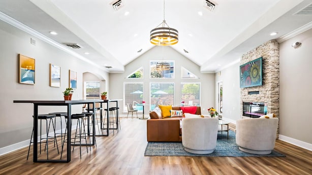 A spacious living area with a high ceiling, a dining area with bar stools, and a stone fireplace. - Landing Apartments - Eureka (Eureka)