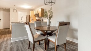 Una cocina moderna con armarios de madera, una isla central y un comedor con una mesa redonda y cuatro sillas.