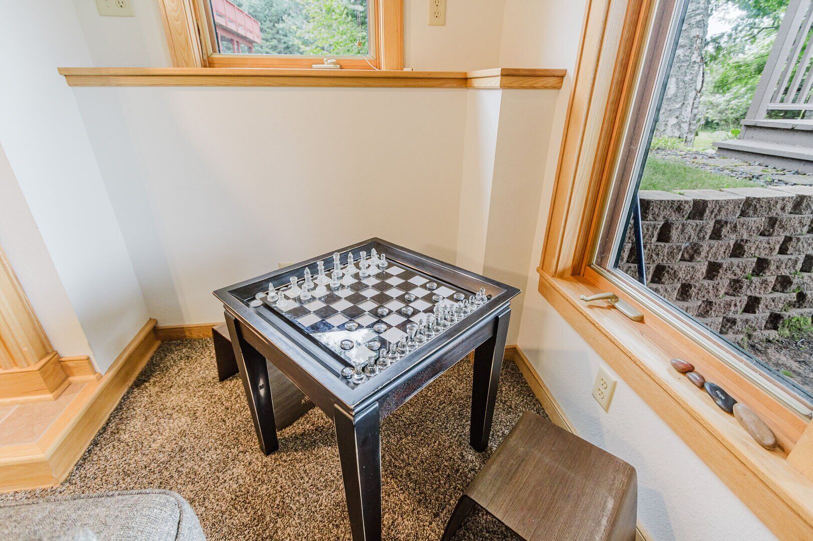 A foosball table in a corner room with a window and a view of a brick wall outside.
