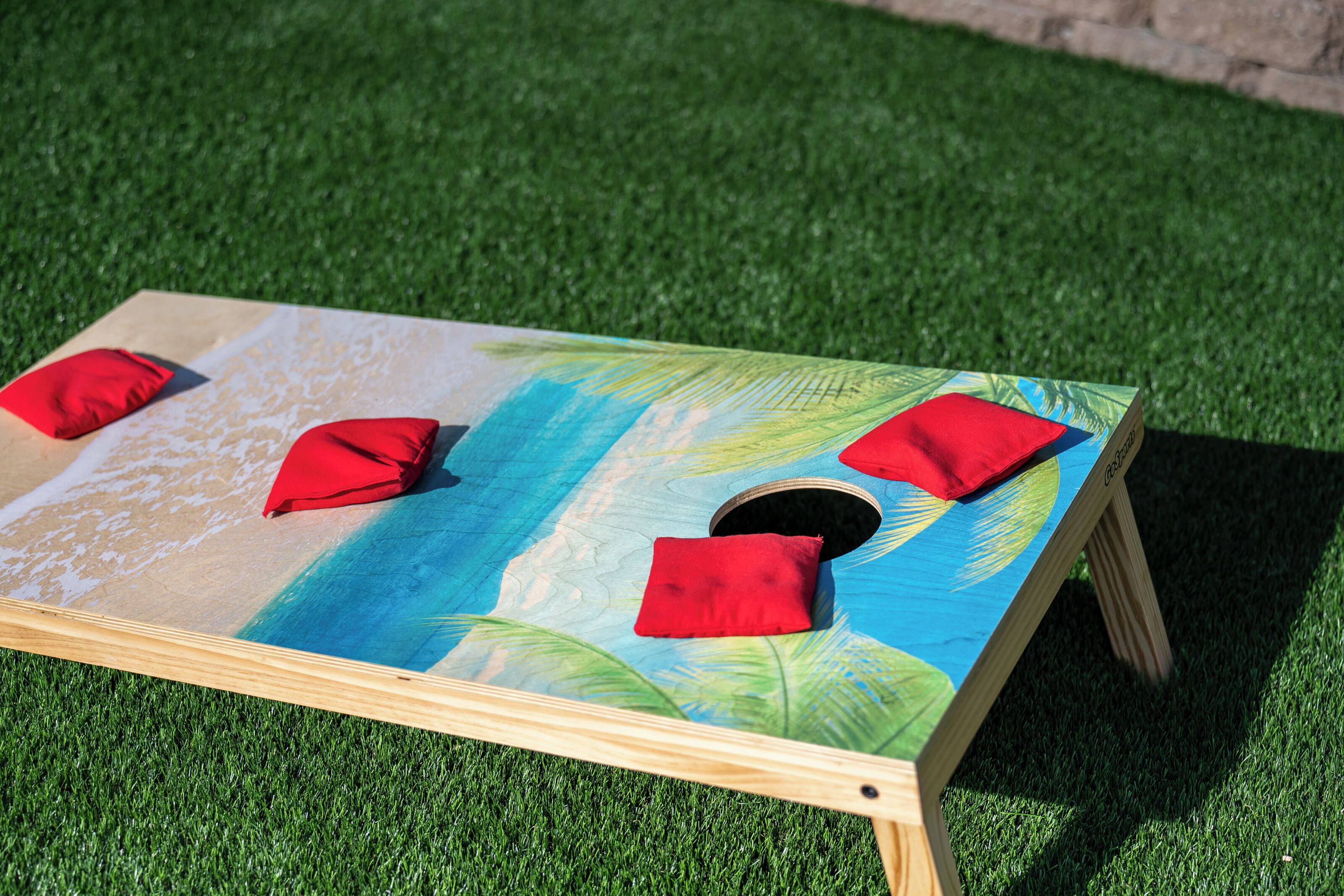 A wooden board game with a tropical design, placed on artificial grass.