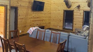 Un interno in legno con un tavolo da pranzo, sedie, un divano e cervi appesi alle pareti.
