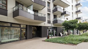 A modern building with multiple balconies and a landscaped area with shrubs. - Krasiński Garden Deluxe Studio (Warszawa)