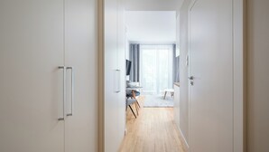 A hallway leading to a dining area with a wooden floor, a dining table, chairs, and a view of a window with curtains. - Krasiński Garden Deluxe Studio (Warszawa)