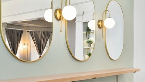 Ein Badezimmer mit drei Wandspiegeln, einem Holzhocker und zwei runden Poufs.