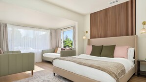 Ein modernes Schlafzimmer mit einem großen Bett, einer Couch und einem Fenster mit Vorhängen.
