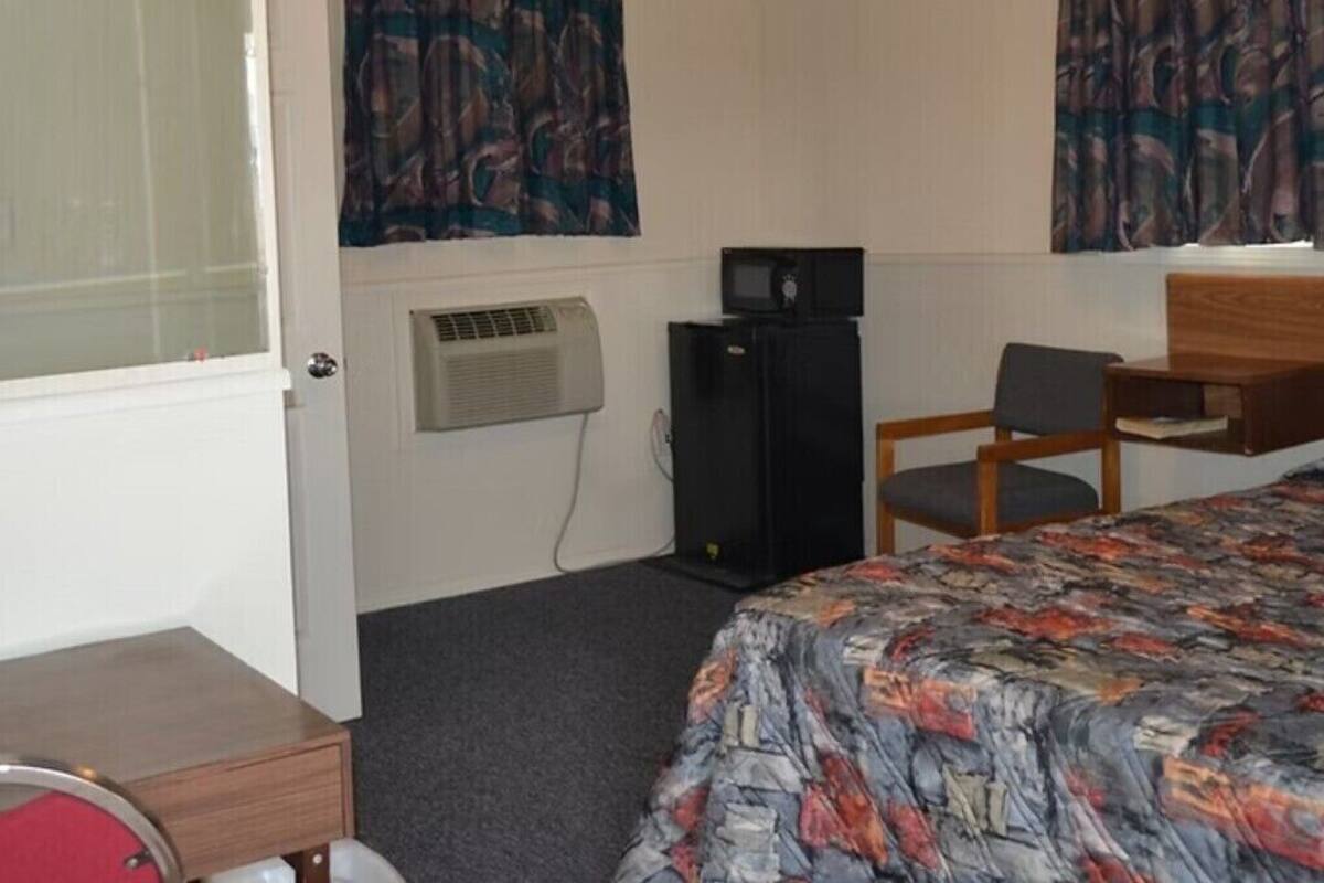 Une chambre d’hôtel équipée d’un lit, d’un bureau, d’une chaise, d’un climatiseur et d’un téléviseur.
