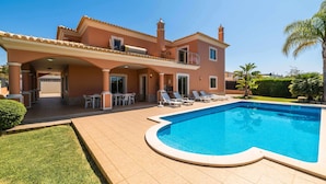 Une maison à deux étages dotée d’une piscine, d’un espace salon extérieur et d’un patio couvert.