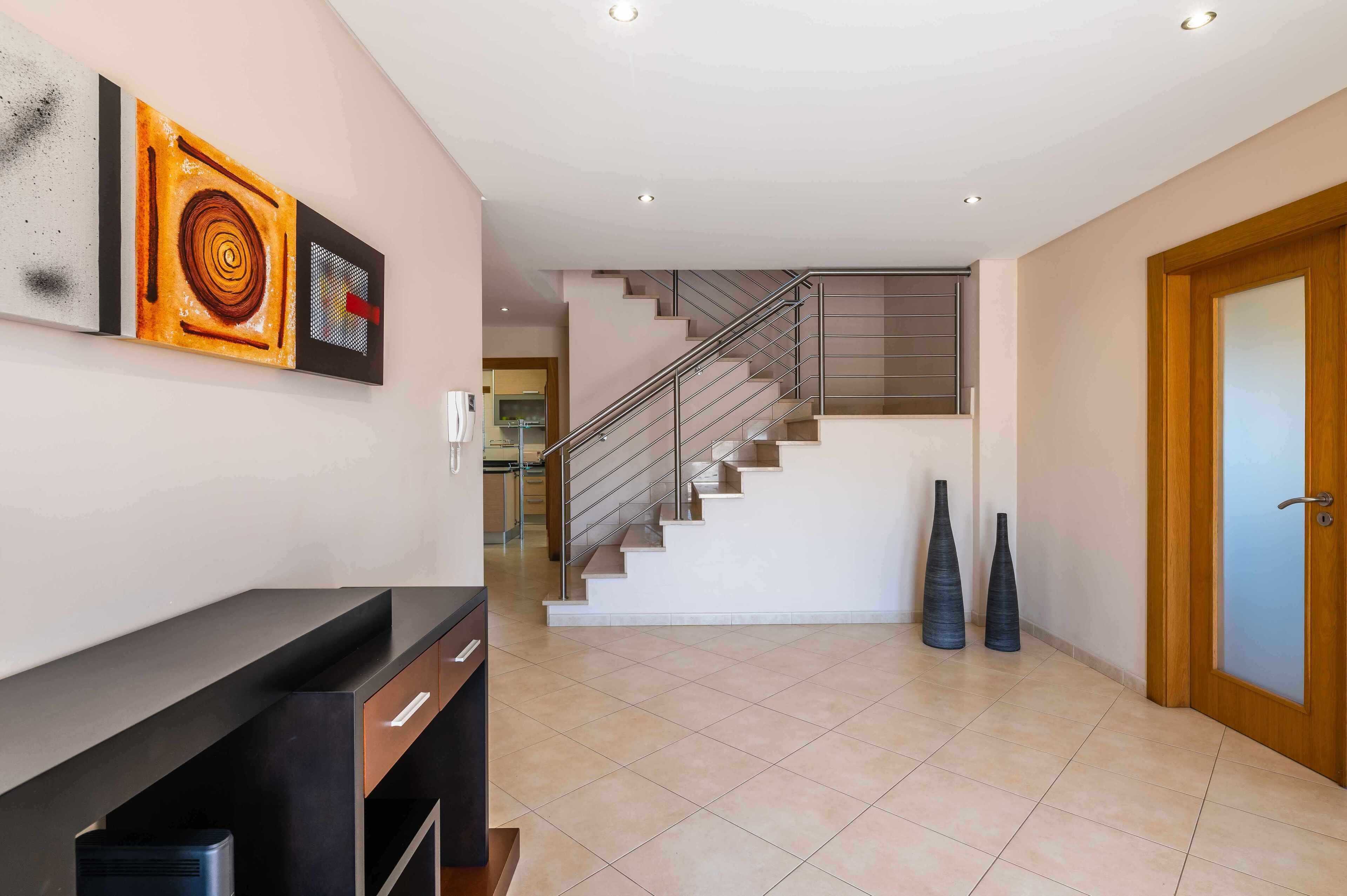 A modern interior with a staircase, a wall-mounted artwork, and a wooden door.