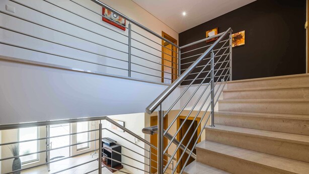 Un escalier moderne avec des rampes en métal et des marches de couleur beige.