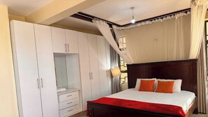 Une chambre avec un grand lit, une armoire et une moquette rouge.