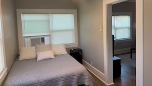 A bedroom with a bed, two nightstands, a ceiling fan, and a window with blinds.