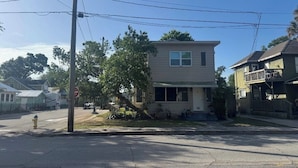 A two-story house with a front yard, a stop sign, and a yellow fire hydrant.