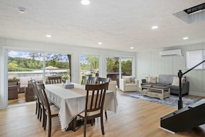 A spacious living area with a dining table, chairs, a sofa, and a staircase.
