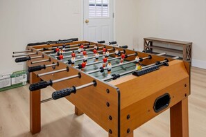 A foosball table in a room with a wooden floor and a white door.