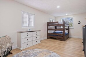 A bedroom with a bunk bed, a dresser, a rug, and a window with blinds.