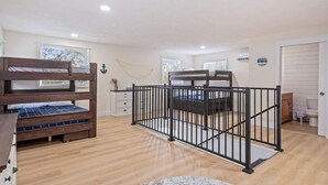 Un dormitorio con literas, un escritorio pequeño, un aparador y una ventana con persianas.