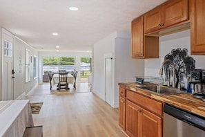A spacious kitchen with wooden cabinets, a dishwasher, and a view of a lake.