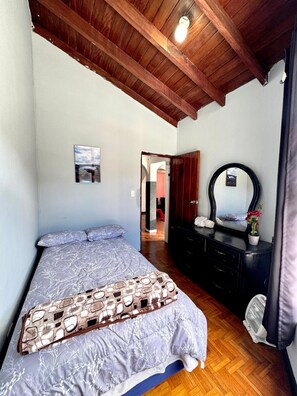 A bedroom with a bed, a dresser, a mirror, and a ceiling light. - Vista & Relax House a few kilometers from the historic center of Quito. (Quito)