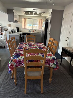 Un coin repas avec une table recouverte d’une nappe à motifs floraux, entourée de chaises en bois.
