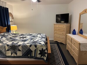 Une chambre à coucher avec un lit, une commode, un téléviseur et un miroir.