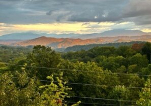 Paisagem montanhosa com árvores e céu nublado.