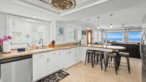 Een moderne keuken met witte kasten, een granieten aanrechtblad en een centraal eiland met barstoelen.