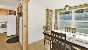 A modern kitchen with wooden cabinets, a built-in oven, and a dining area with a table and chairs.