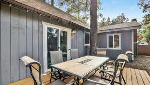 A patio with a table and chairs, a sliding glass door, and a small attached structure with a window.