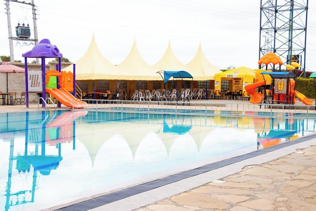 Una piscina con tobogán, un área de juegos y una zona cubierta con toldos.