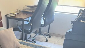 Un lit recouvert d’une couverture matelassée, un bureau avec une chaise et une fenêtre à l’arrière-plan.