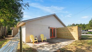 Un petit bâtiment d’un seul étage, avec une porte rouge et une terrasse en bois. On y trouve deux chaises jaunes.