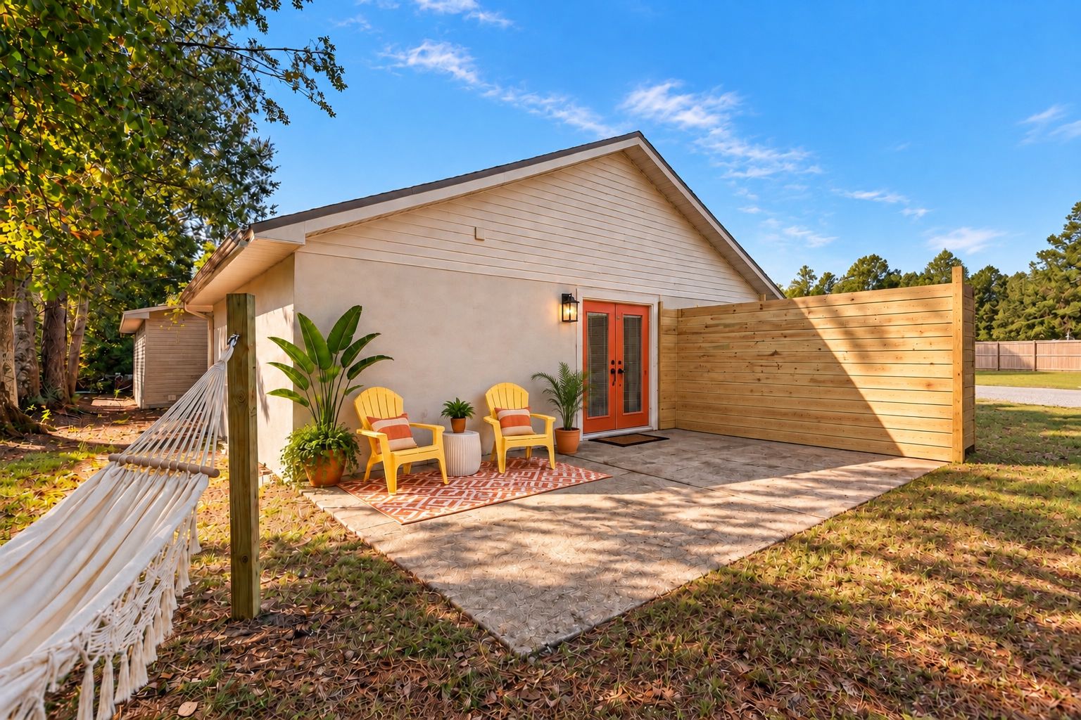 A single-story building with a sloped roof, a wooden fence, and a hammock.