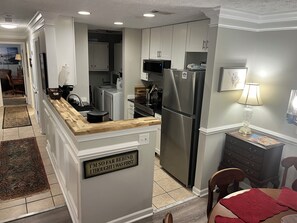 Una cocina moderna con electrodomésticos de acero inoxidable, encimera de madera y un cartel en la pared.